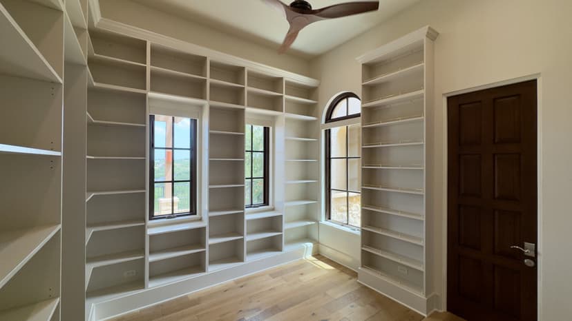 Built-in white library bookcases running to the ceiling around an arched window