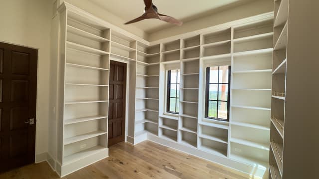 Floor-to-ceiling white built-in library shelving wrapping a room in San Antonio