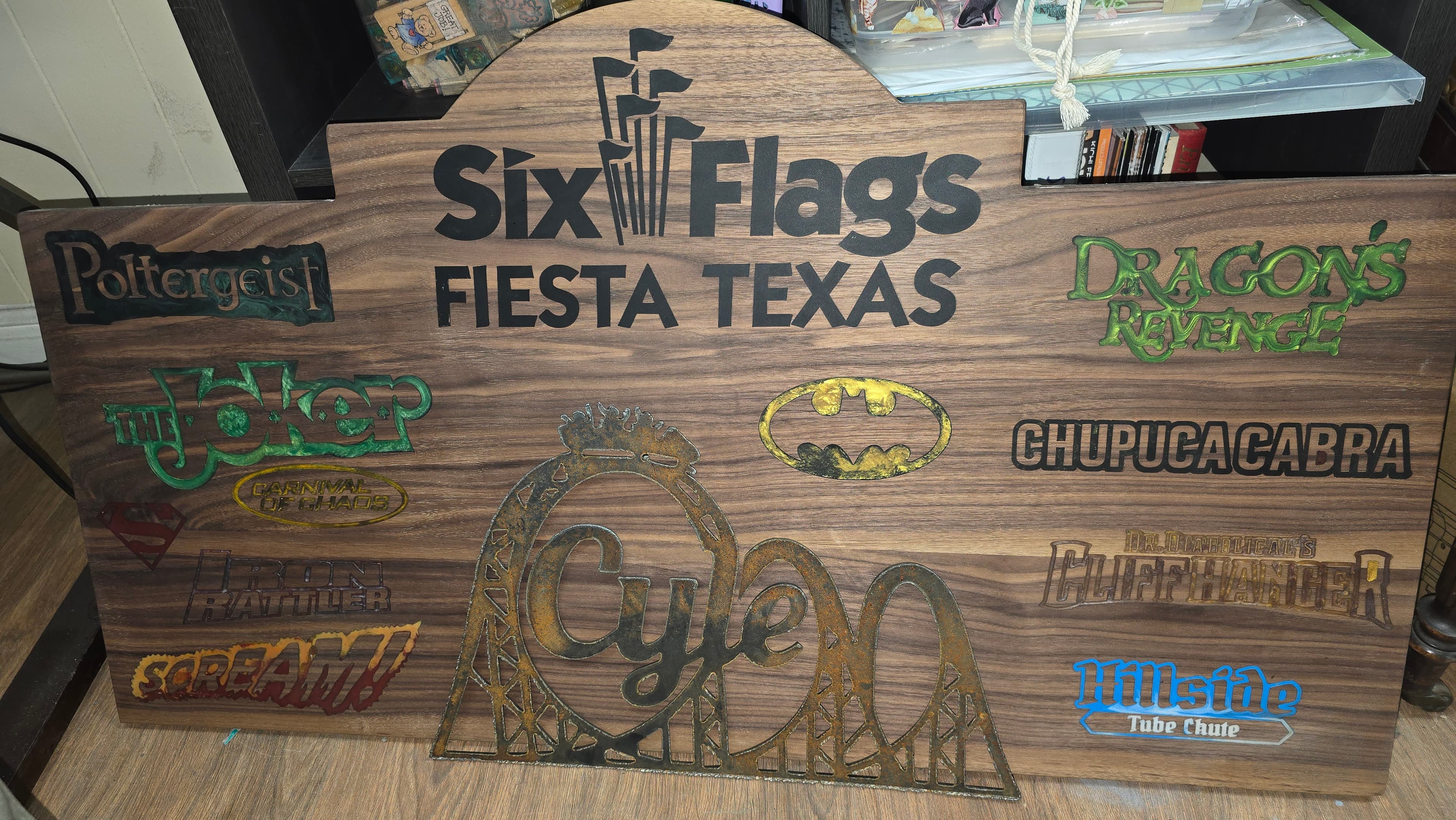 Workshop view of the custom CNC engraved Six Flags Fiesta Texas walnut sign before mounting. This piece showcases the precision of CNC routing combined with artisan epoxy fill work and a plasma-cut roller coaster centerpiece, created in collaboration with Black Dog Forge.