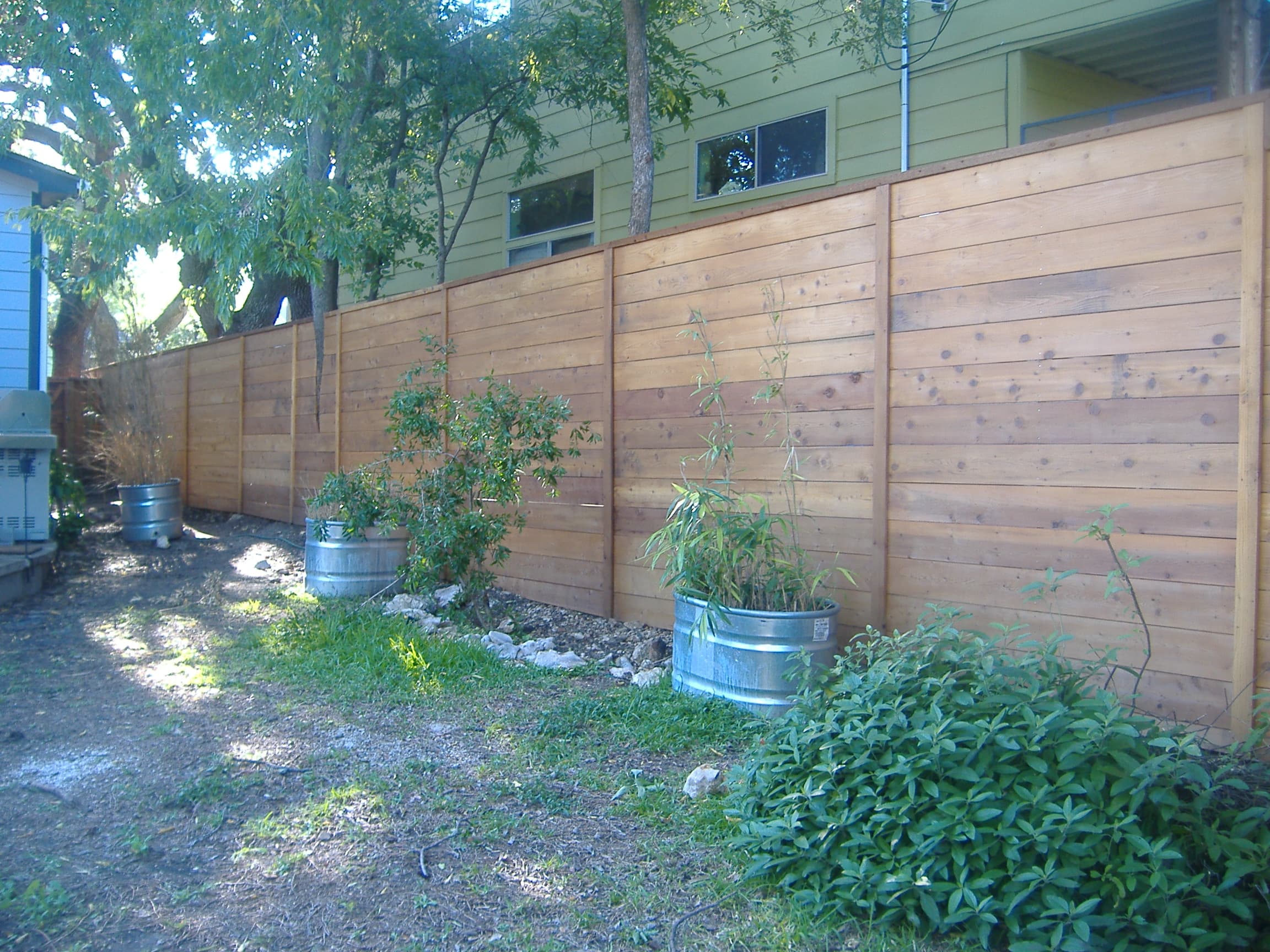 Natural cedar horizontal fence running the length of a side yard, its warm untreated tone blending into the landscaping. The horizontal board pattern creates a modern privacy screen that keeps the space feeling open and bright.