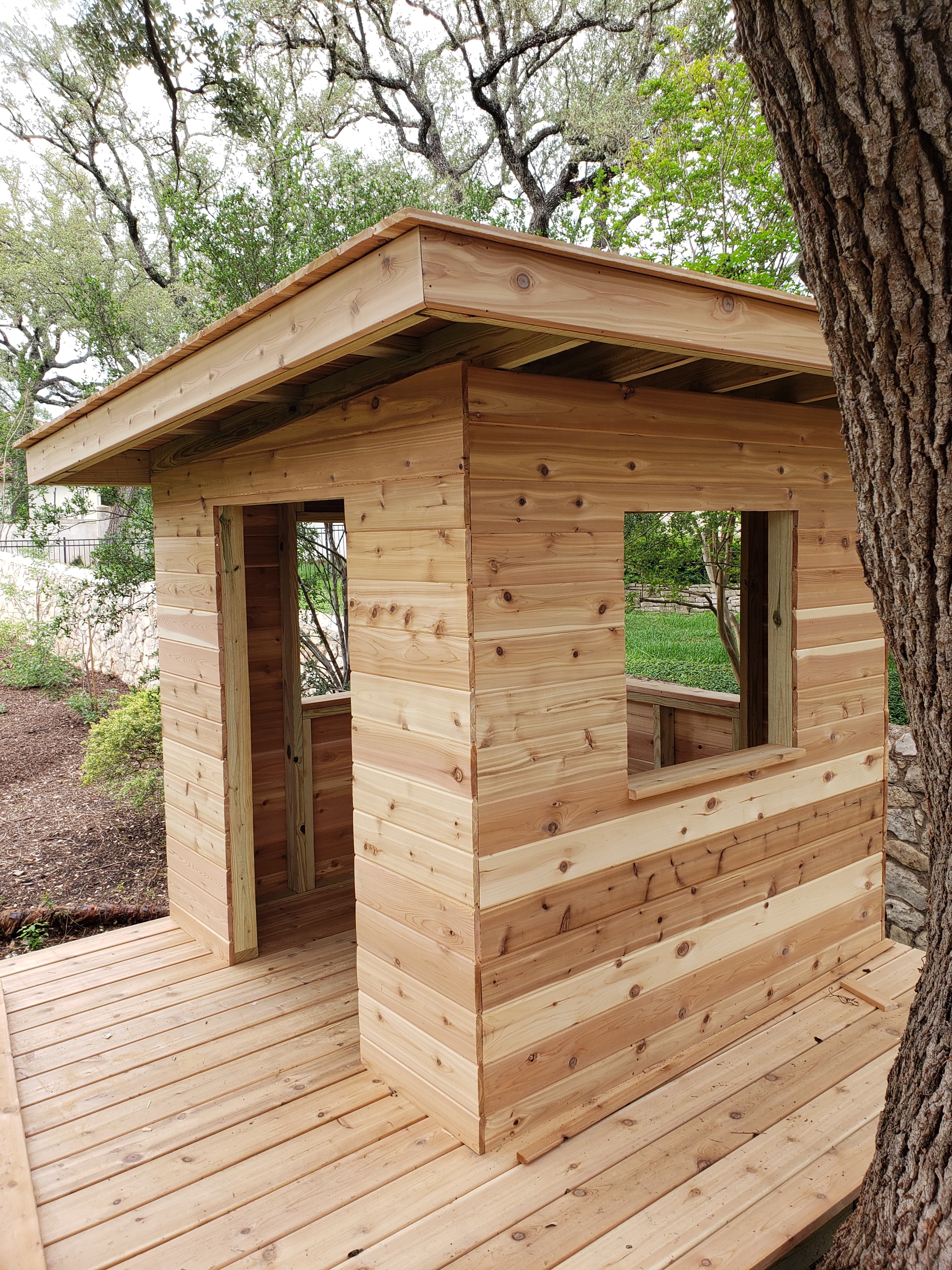 Professional outdoor living project featuring cedar deck playhouse with windows