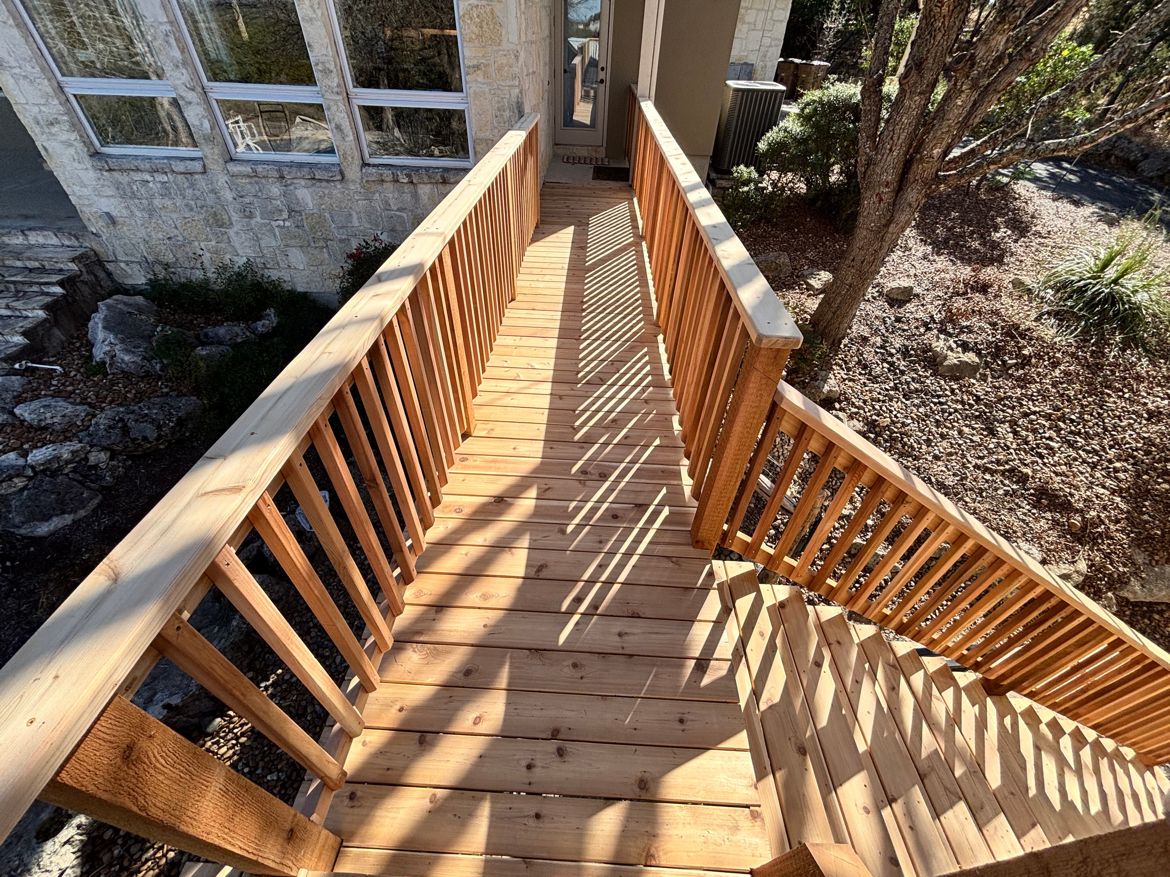 Fresh cedar deck replacement with custom staircase and railing at a hillside property in Cordillera Ranch, Boerne. Built with pressure-treated framing and cedar decking and railing, this project replaced an aging deck. The finished product was stained for long-term protection against Texas weather.