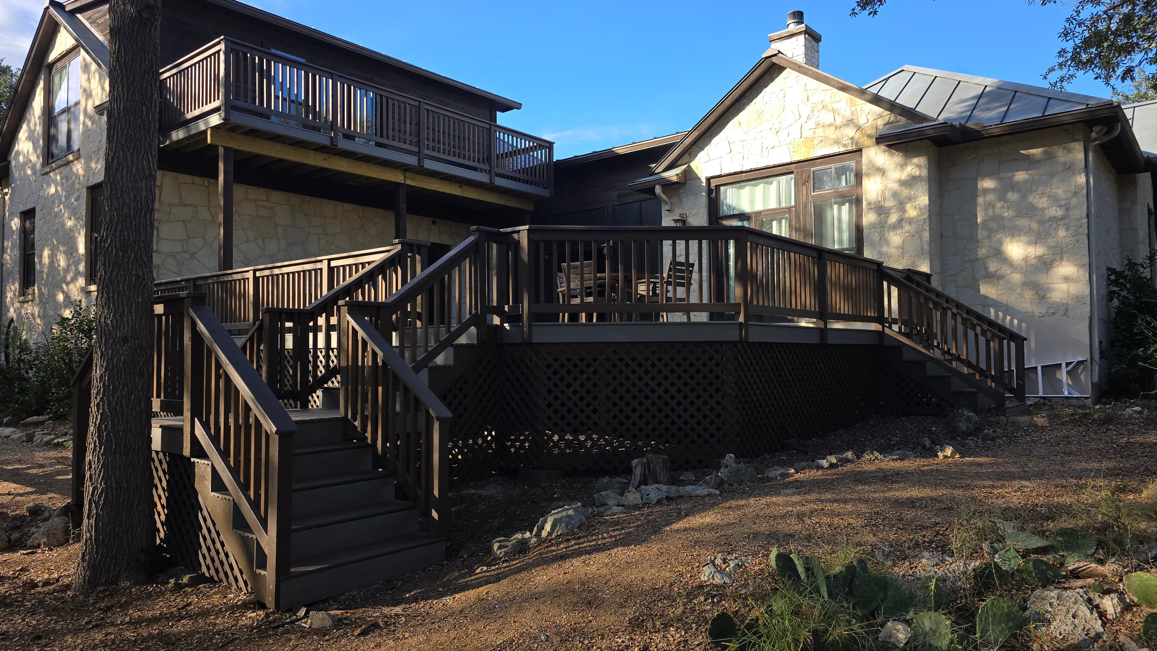 Expansive composite deck with cedar railing at a Cordillera Ranch property in Boerne. This complete tear-down and rebuild features composite decking for durability and low maintenance, paired with cedar railing and skirting for a natural Hill Country aesthetic. The generous entertaining space sits among mature live oaks.