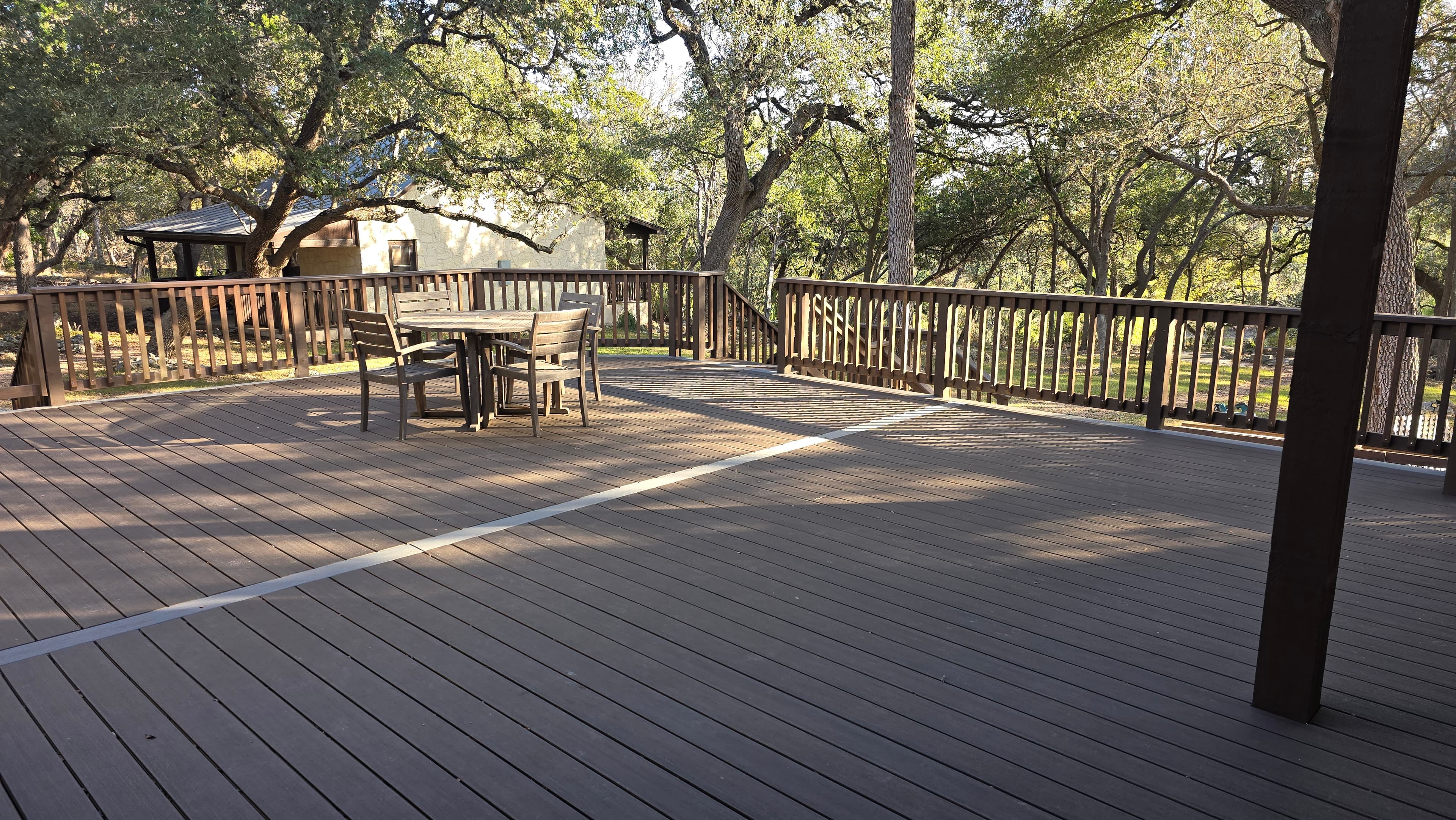 Multi-level composite deck rebuild featuring cedar stairs, railing, and lattice skirting at a Hill Country stone home in Cordillera Ranch. The design includes upper and lower deck levels connected by custom stairs, with lattice skirting panels for a finished look underneath.