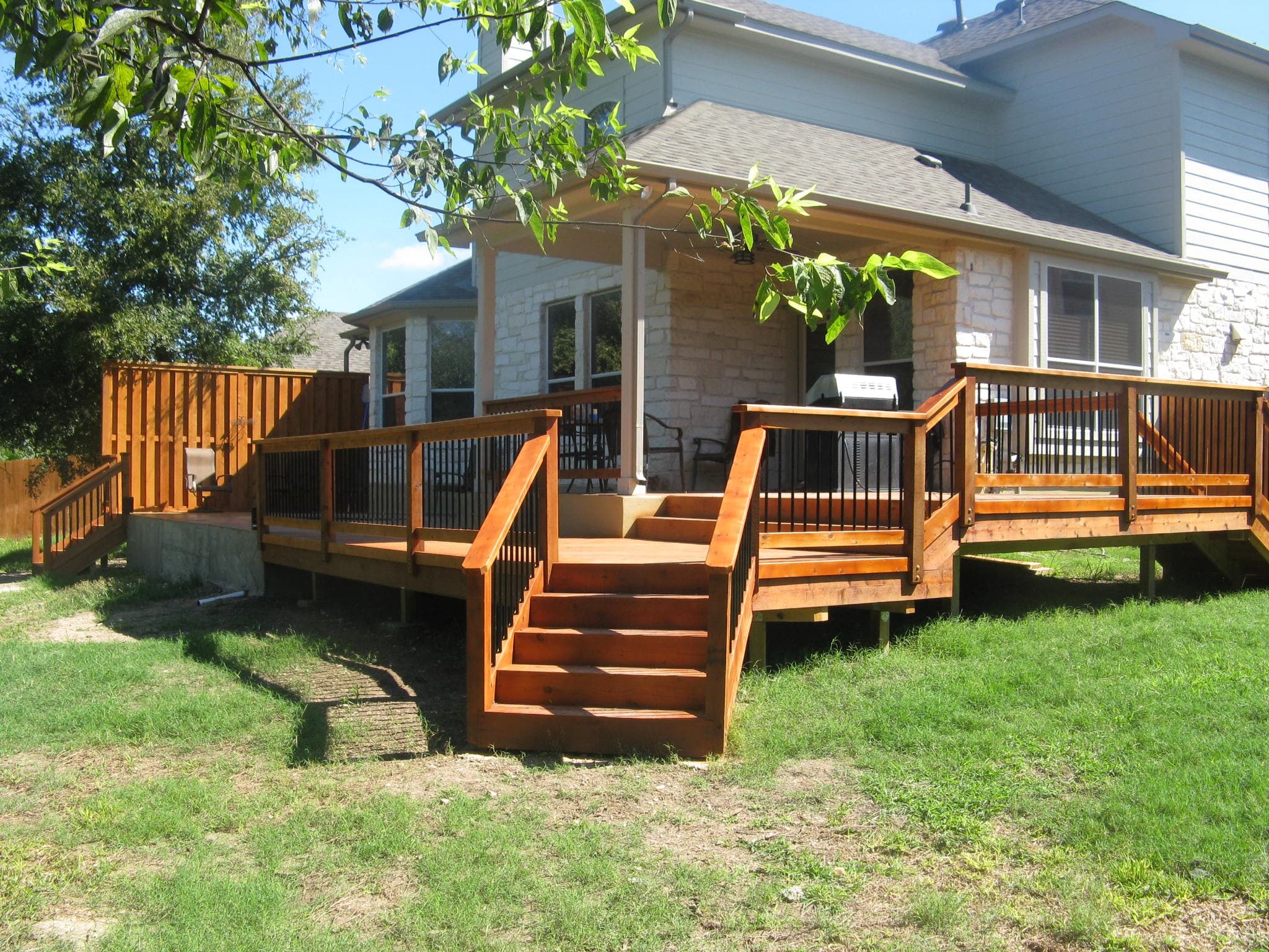 Stained wraparound deck with wide center stairs and black metal balusters