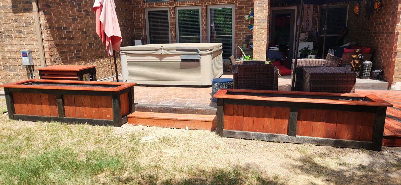 Two-tone stained cedar planter boxes and deck steps beside a backyard patio