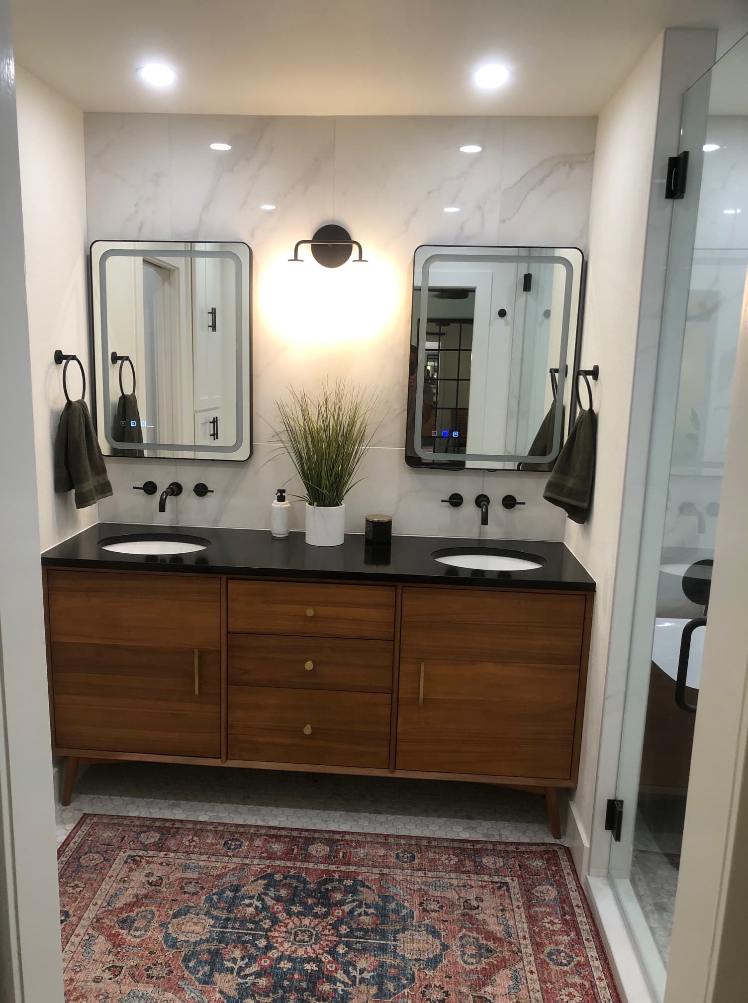 Remodeled New Braunfels primary bathroom with a wood dual vanity, porcelain tile and black fixtures
