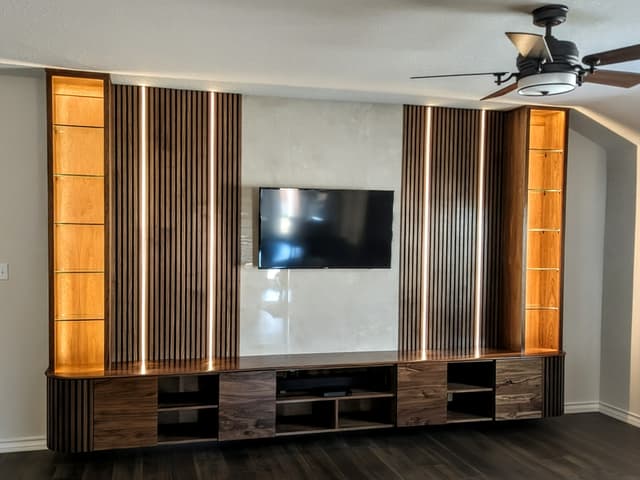 Custom entertainment center with a vertical wood slat wall, floating credenza and LED-lit display shelving, San Antonio