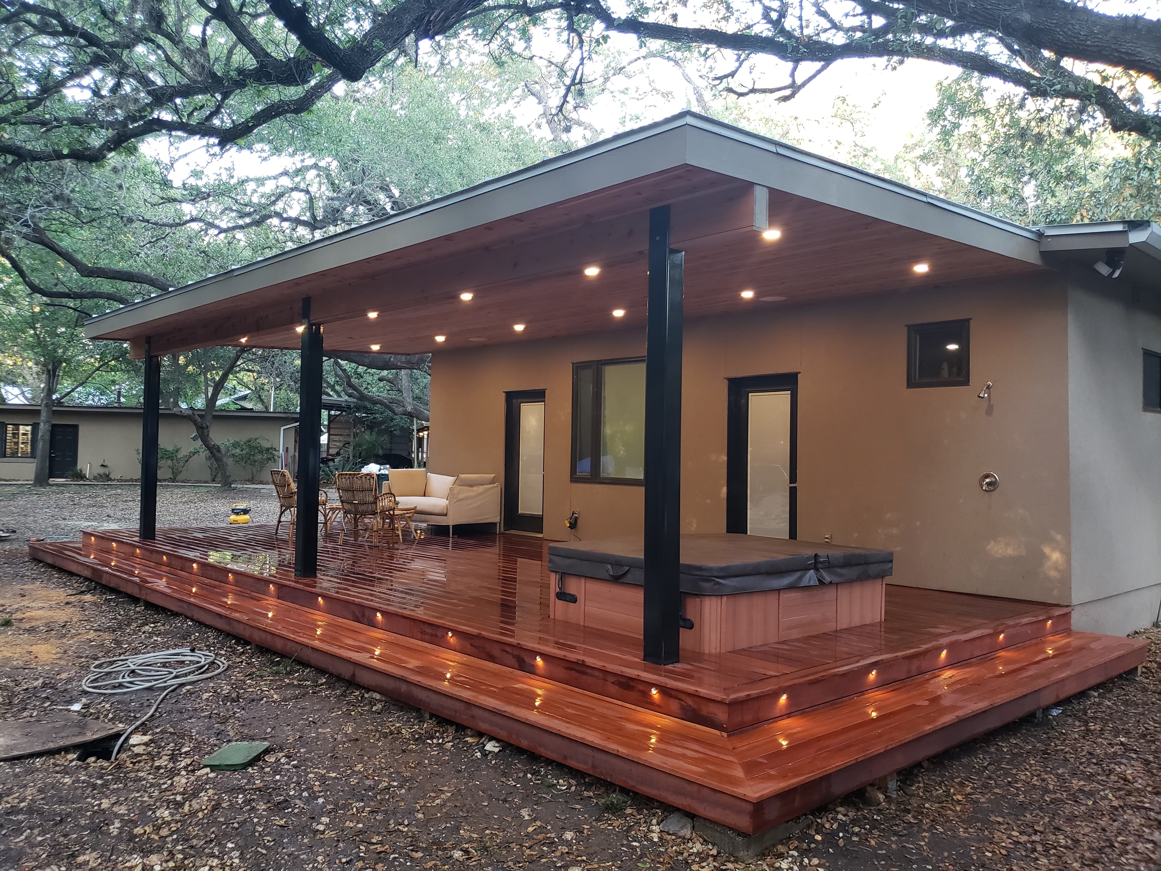 Tigerwood deck with a steel-frame pergola and recessed lighting under mature oaks in Castle Hills